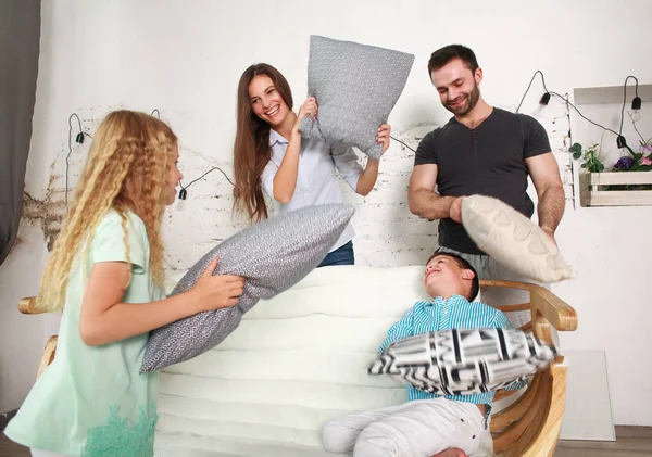 Młode rodziny i dwoje dzieci grać w domu walki z poduszkami — Zdjęcie stockowe