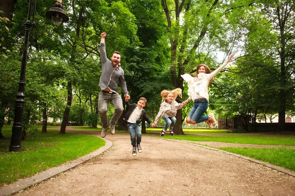 Alegre familia feliz en el parque de verano juntos saltando para divertirse — Foto de Stock