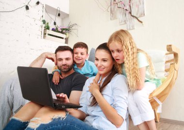 Evde iki çocuklu mutlu aile eğlence üstünde laptop arıyorum.