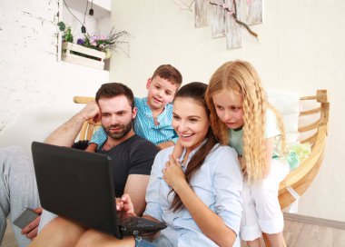 Evde iki çocuklu mutlu aile eğlence üstünde laptop arıyorum.