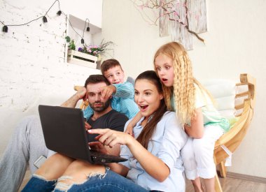 Evde iki çocuklu mutlu aile eğlence üstünde laptop arıyorum.