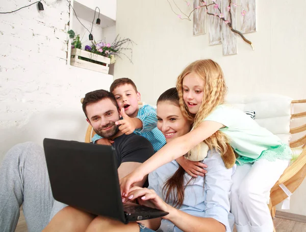 Evde iki çocuklu mutlu aile eğlence üstünde laptop arıyorum.