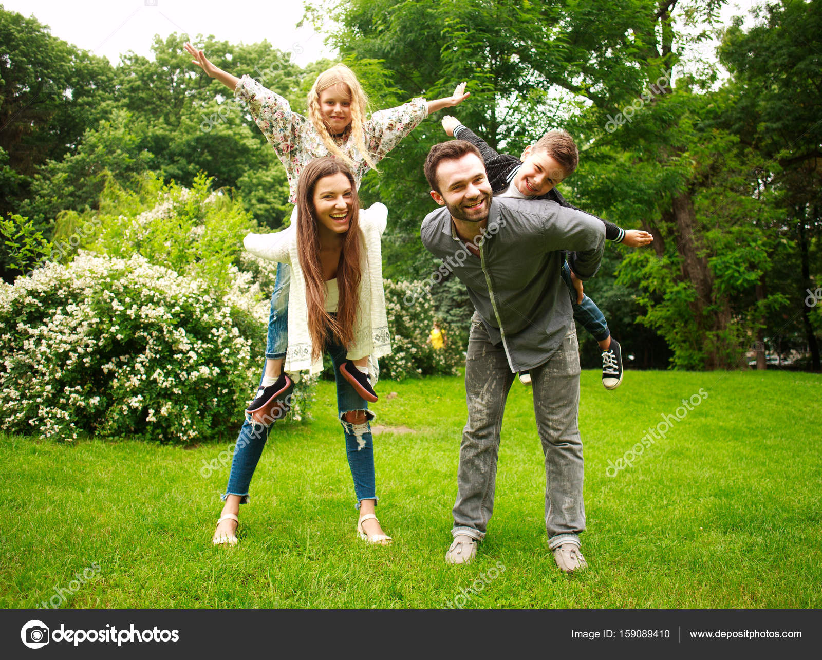 Happy joyful family in park fun playing imitation flight Stock Photo by