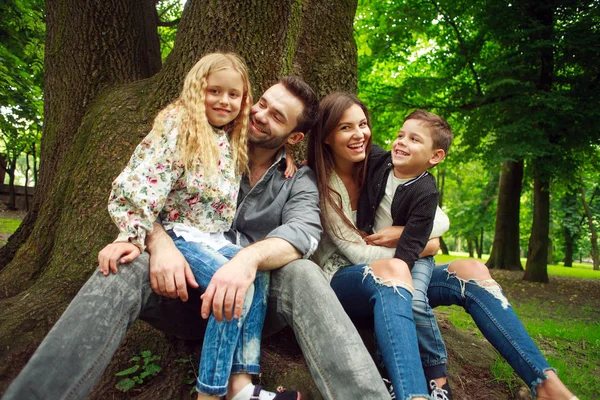 Šťastná rodina sedí pohromadě na stromě v letním lese — Stock fotografie