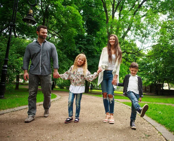 Familia feliz caminando de la mano en el parque verde de la ciudad — Foto de Stock