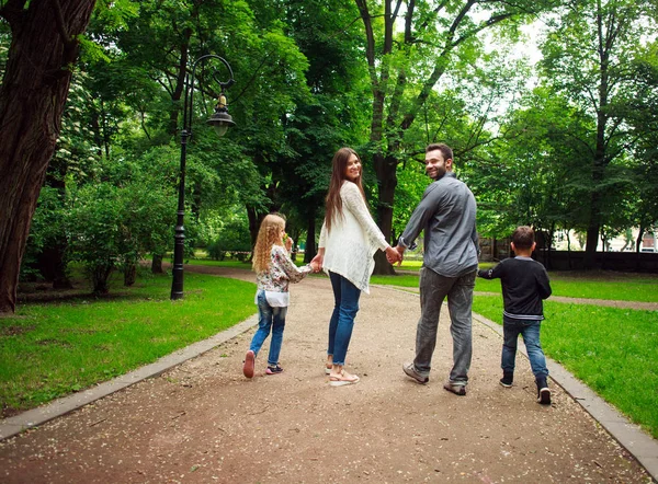 Familia feliz caminando de la mano en el parque verde de la ciudad — Foto de Stock