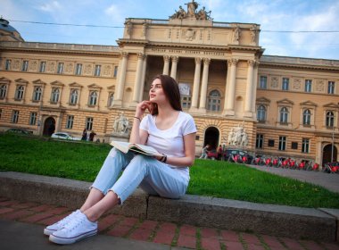 Dalgın öğrenci kız Üniversitesi arka plan üzerinde kitapla