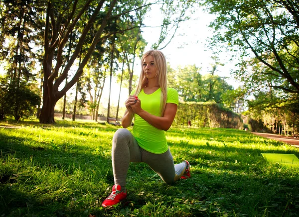 Sportig smal kvinna gör fitnessövningar stretching i park — Stockfoto