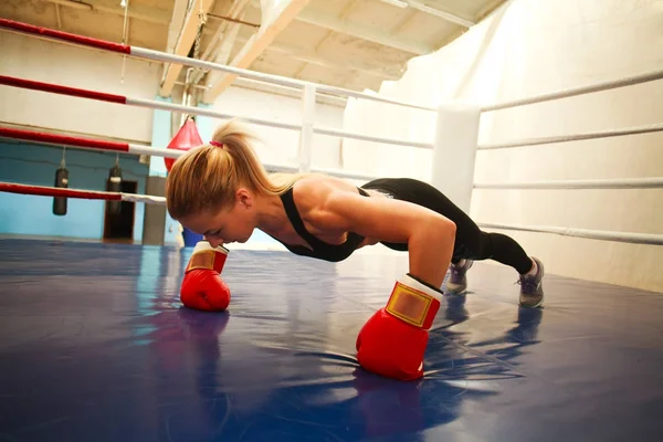 Atlética joven en guantes de boxeo en el gimnasio haciendo flexiones en r —  Fotos de Stock
