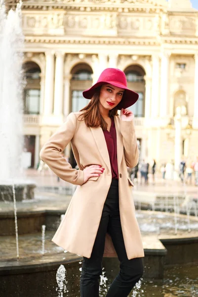 Jeune belle femme en manteau et chapeau violet sur la ville touristique de rue — Photo