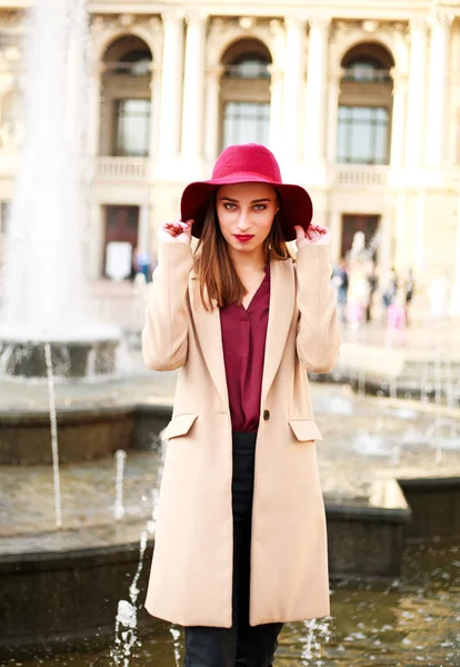 Νεαρή όμορφη γυναίκα στο παλτό και μοβ καπέλο στην οδό τουριστική πόλη — Φωτογραφία Αρχείου