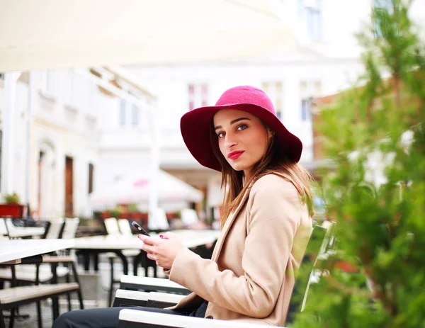 Elegante joven en la cafetería de la calle con teléfono en el fondo de la ciudad —  Fotos de Stock