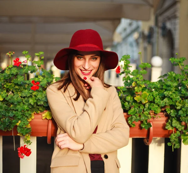 Linda chica en abrigo en la calle ciudad turística con flores en la puesta del sol —  Fotos de Stock