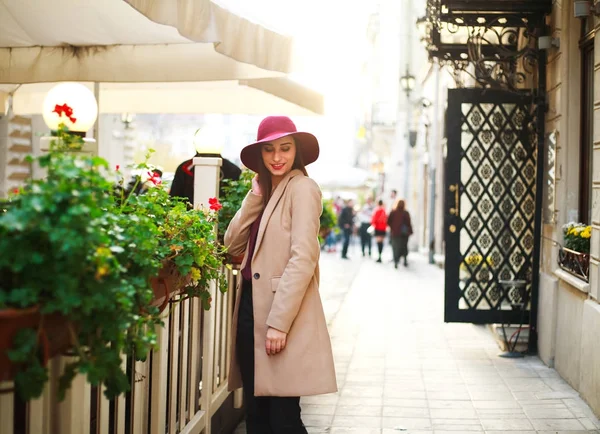 Jolie fille en manteau sur la rue ville touristique avec des fleurs sur le coucher du soleil — Photo