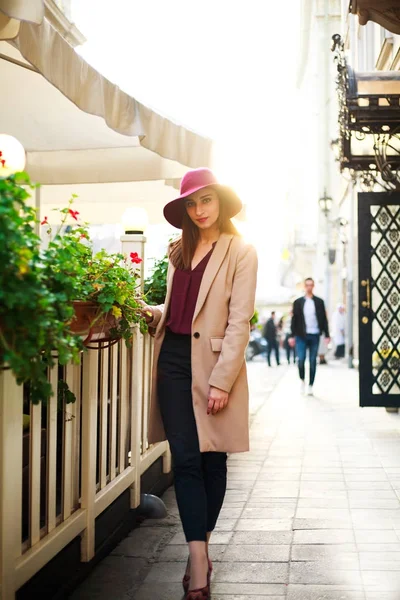 Jolie fille en manteau sur la rue ville touristique avec des fleurs sur le coucher du soleil — Photo