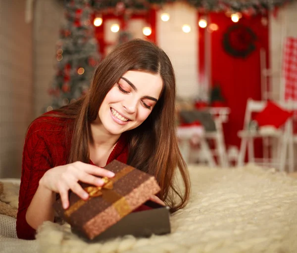 Žena otevřít okno s darem na pozadí vánočních ozdob — Stock fotografie