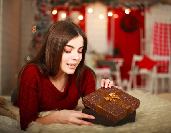 Kvinnan öppnar rutan med gåva på bakgrund av juldekorationer — Stockfoto