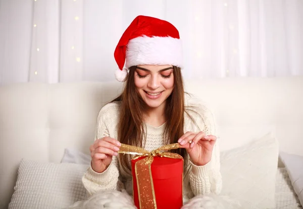 Счастливая улыбающаяся женщина в красной кепке с подарком на кровати — стоковое фото