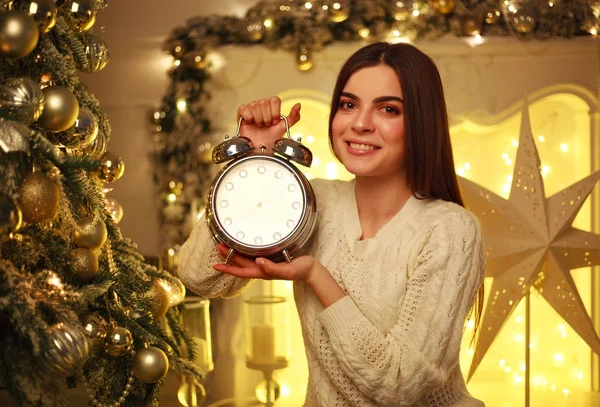 Девушка с будильником дома в рождественских украшениях — стоковое фото