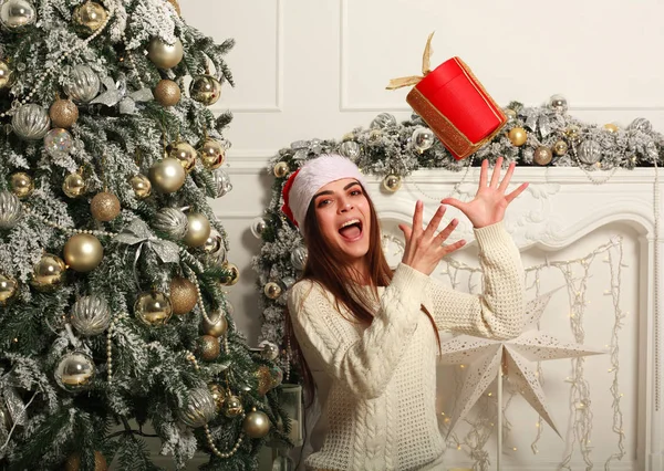 Vrolijke vrouw met gave in KERSTMUTS op achtergrond van Kerstmis — Stockfoto