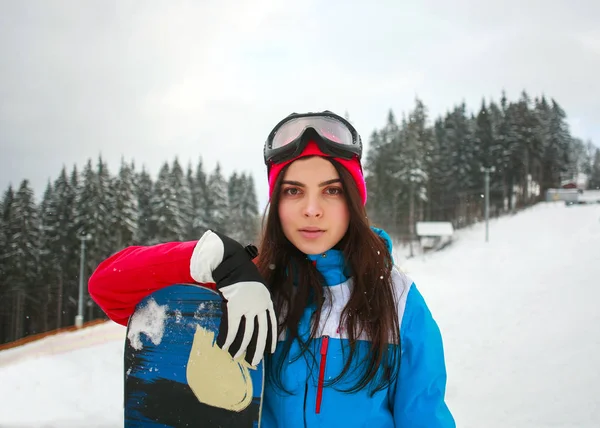 松の背景のスキー場で冬の女性スノーボーダー — ストック写真