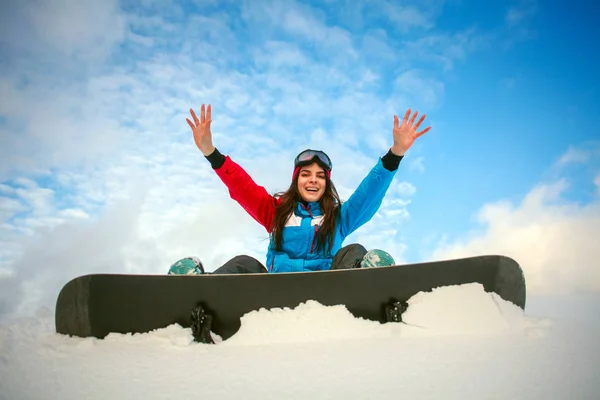 Радісна жінка сноубордист сидить на вершині гори на блакитному небі — стокове фото