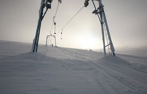Skilift in sneeuw bewolkte winterlandschap in mistige bergen — Stockfoto