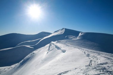 Beyaz zirveleri karla kaplı dağ güneşli mavi gökyüzü üzerinde