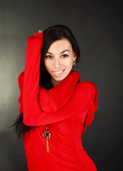 スタジオで黒の背景に赤いドレスで笑顔のファッション女性 — ストック写真