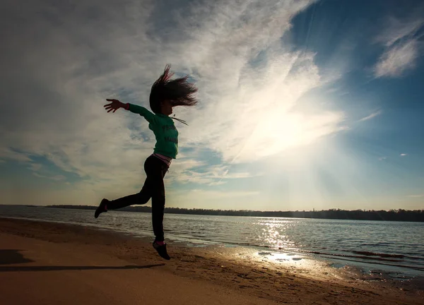 Mujer salto en la playa en el amanecer cielo fondo, concepto de libertad — Foto de Stock