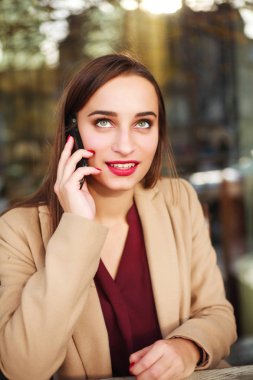 Paltolu güzel kız cep telefonu yaz kafede kullanır.