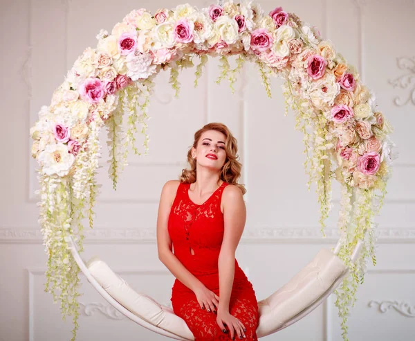 Mujer alegre elegante en vestido rojo en swing en flores —  Fotos de Stock