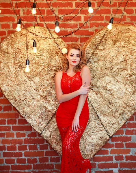 Okouzlující žena v červených šatech na zlaté srdce ve studiu — Stock fotografie