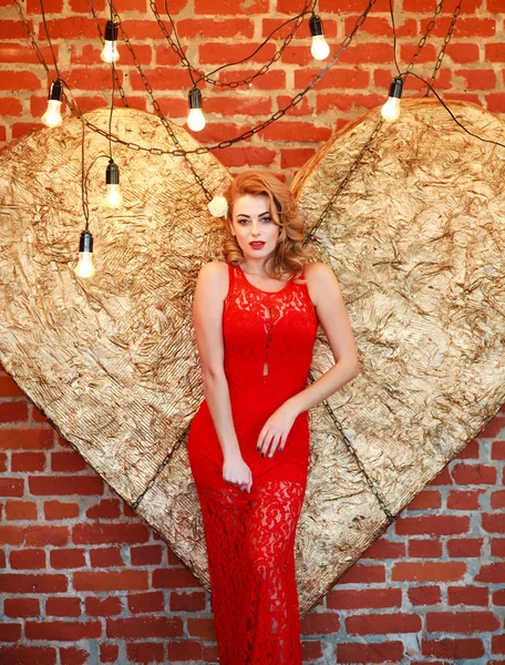 Affascinante donna in abito rosso sul cuore d'oro in studio — Foto Stock