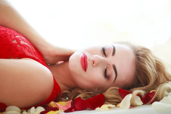 Красива модна жінка в пелюстках червоної троянди на білому — стокове фото