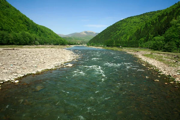 Stroom van de rivier onder bos bergen op de achtergrond van de blauwe hemel — Stockfoto