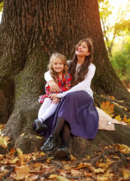 Joyful company of children sits carefree on tree in forest