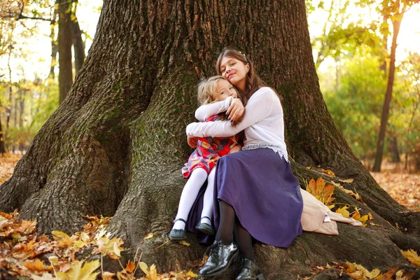 A companhia alegre de crianças senta-se despreocupada na árvore na floresta — Fotografia de Stock