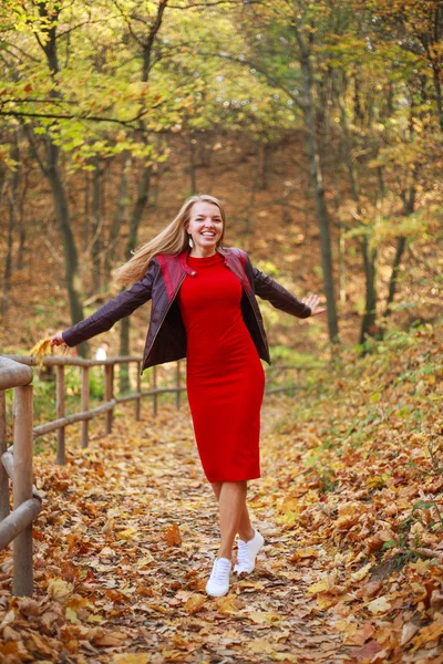 Szczęśliwa młoda kobieta w czerwonej sukience niedbale bawiąca się w lesie — Zdjęcie stockowe