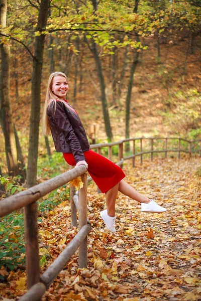 Fröhliche junge Frau in rotem Kleid hat leichtsinnig Spaß im Wald — Stockfoto