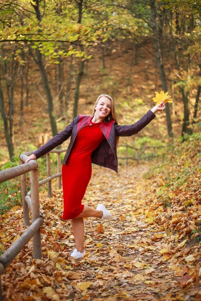 Счастливая молодая женщина в красном платье небрежно развлекается в лесу — стоковое фото
