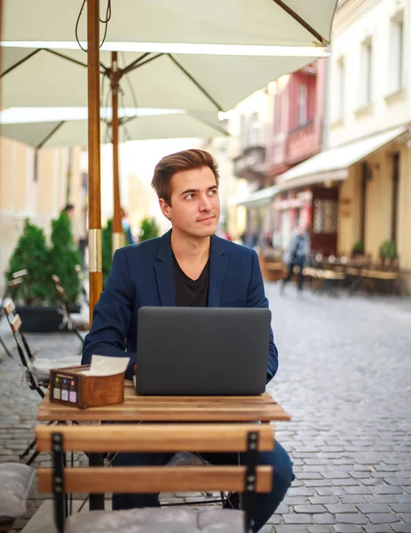 Молодий хлопець бізнесмен з ноутбуком за столом літнього кафе — стокове фото