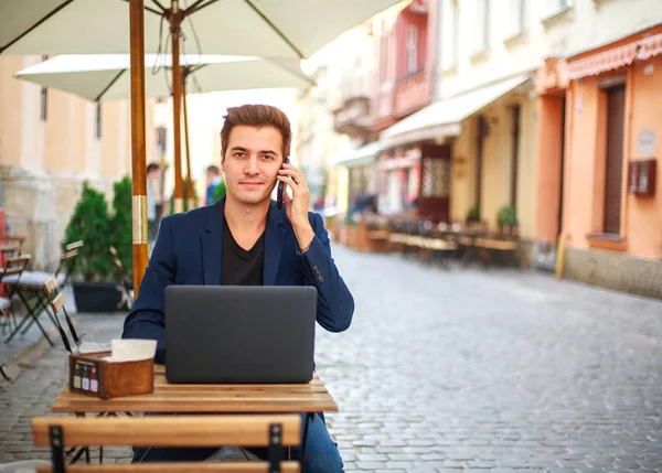 Молодий хлопець бізнесмен з ноутбуком за столом в літньому кафе — стокове фото