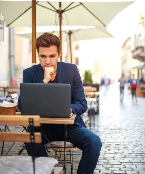 Молодий хлопець бізнесмен з ноутбуком за столом літнього кафе — стокове фото
