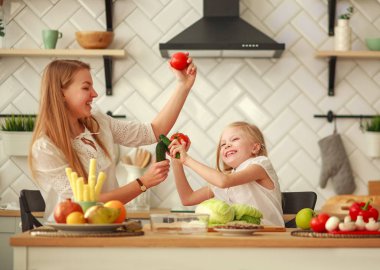 Joyful mother with daughter at home in kitchen having fun play