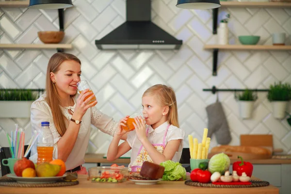 Anne ve kızı mutfakta portakal suyu içiyorlar. Telifsiz Stok Imajlar