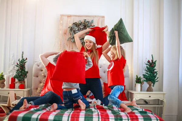 Young family with children having fun at home fighting pillows — Stockfoto