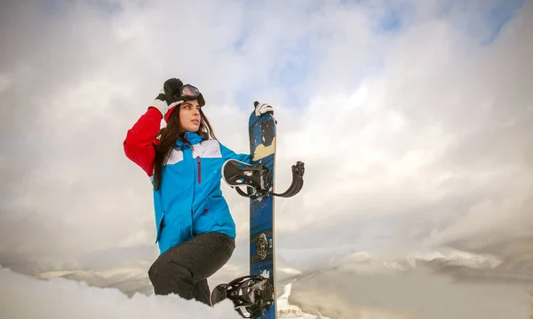 Jovem com snowboard alto em montanhas de inverno escalada — Fotografia de Stock