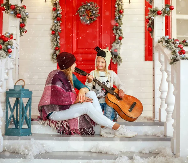 Молодая мать и дочь на крыльце праздничного Рождественского дома — стоковое фото