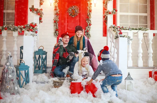 Радостная семья с детьми, играющими в снежки во дворе — стоковое фото